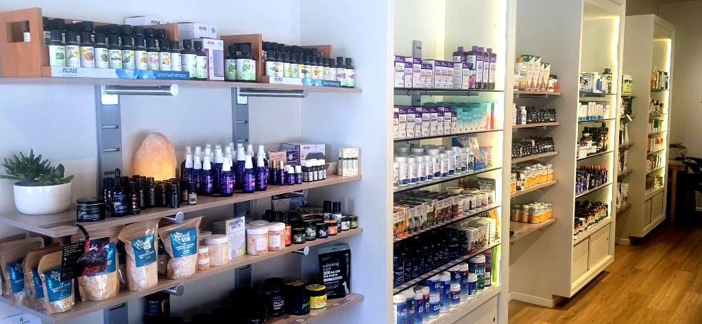 Lit apothecary shelves stocked with vitamins, supplements, and botanical remedies